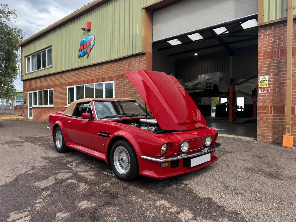 Red Aston Martin V8 Volante with its bonnet raised outside the IceBlastPro workshop