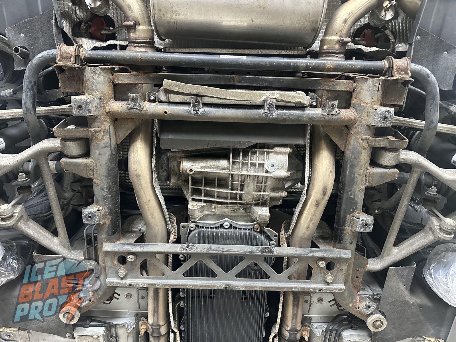 Before – surface corrosion – The rear subframe on arrival: surface corrosion across the crossmember, brackets and anti-roll bar, with the original coating starting to lift and fail.