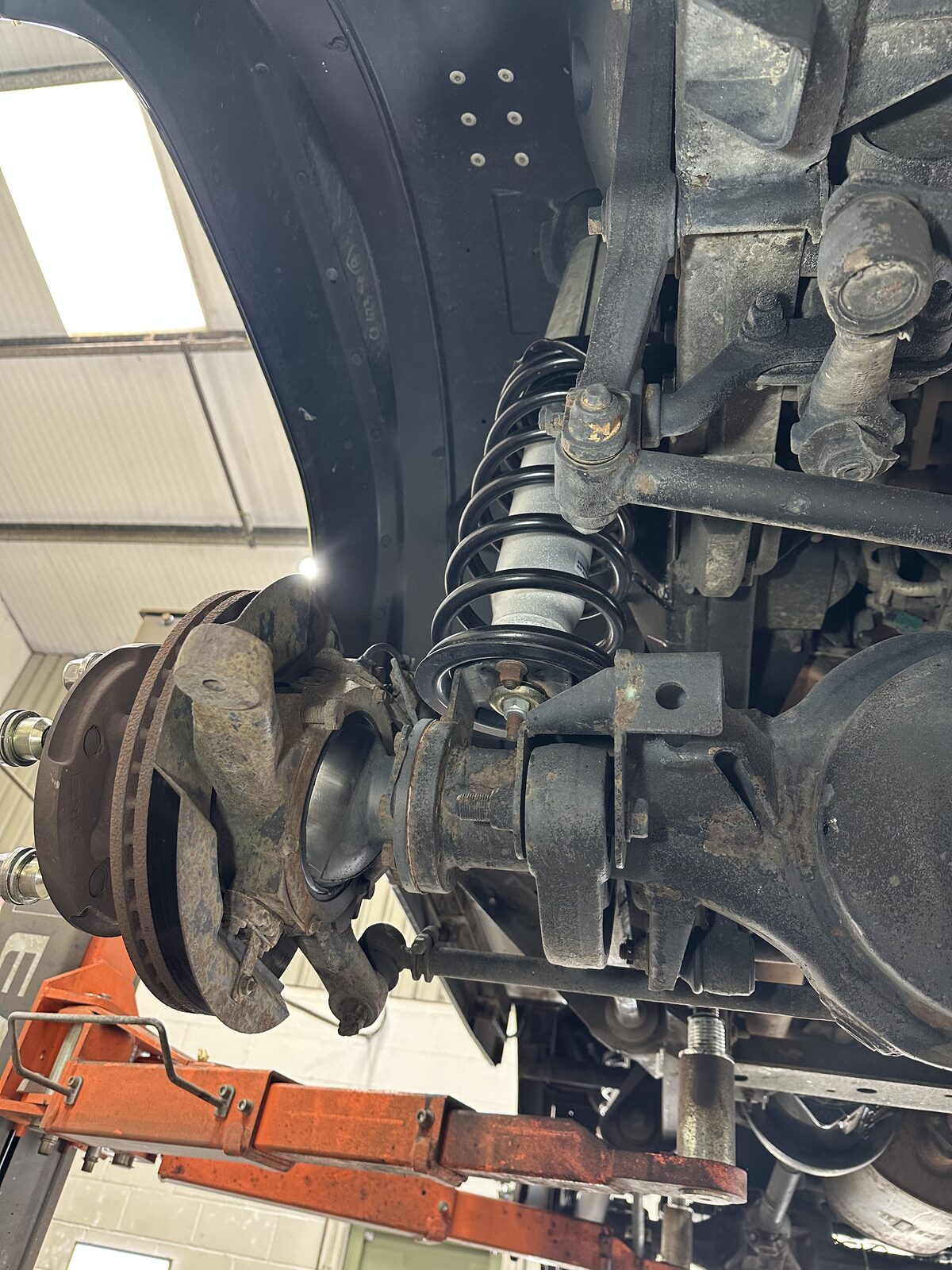 Front driver's side – Coil spring, hub and brake area showing surface corrosion and ingrained dirt before any cleaning began.
