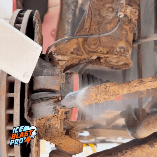 Dry ice blasting exposing rust on a car underbody suspension component before treatment.
