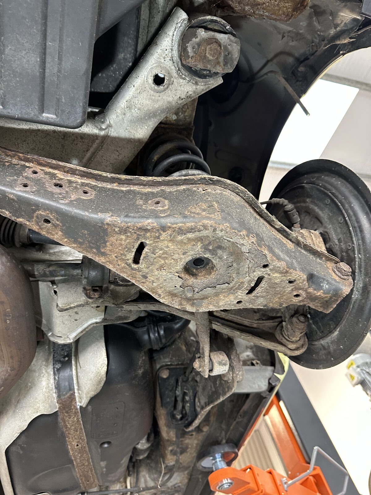 Lower rear suspension arm of a 2007 Volkswagen Golf R32 before treatment, showing surface corrosion and flaking rust