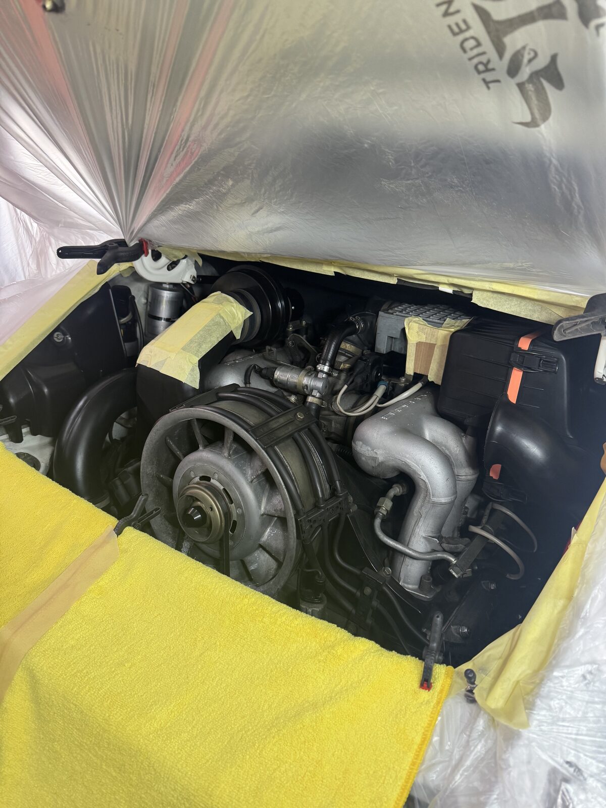 The Porsche 911 Carrera CS engine bay masked off with covers and tape, prepped and ready for dry ice cleaning