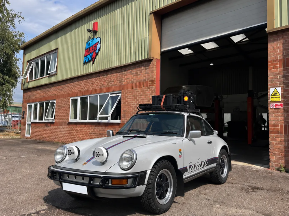 White Porsche 911 Safari with rally lights and roof equipment outside the IceBlastPro workshop
