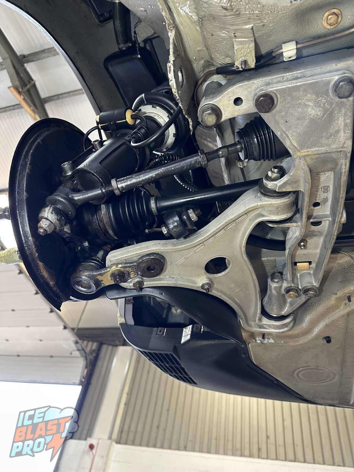 The same Porsche 911 Carrera 4 front lower arm after dry ice cleaning – the alloy arm back to a clean silver finish with the Porsche stamping visible