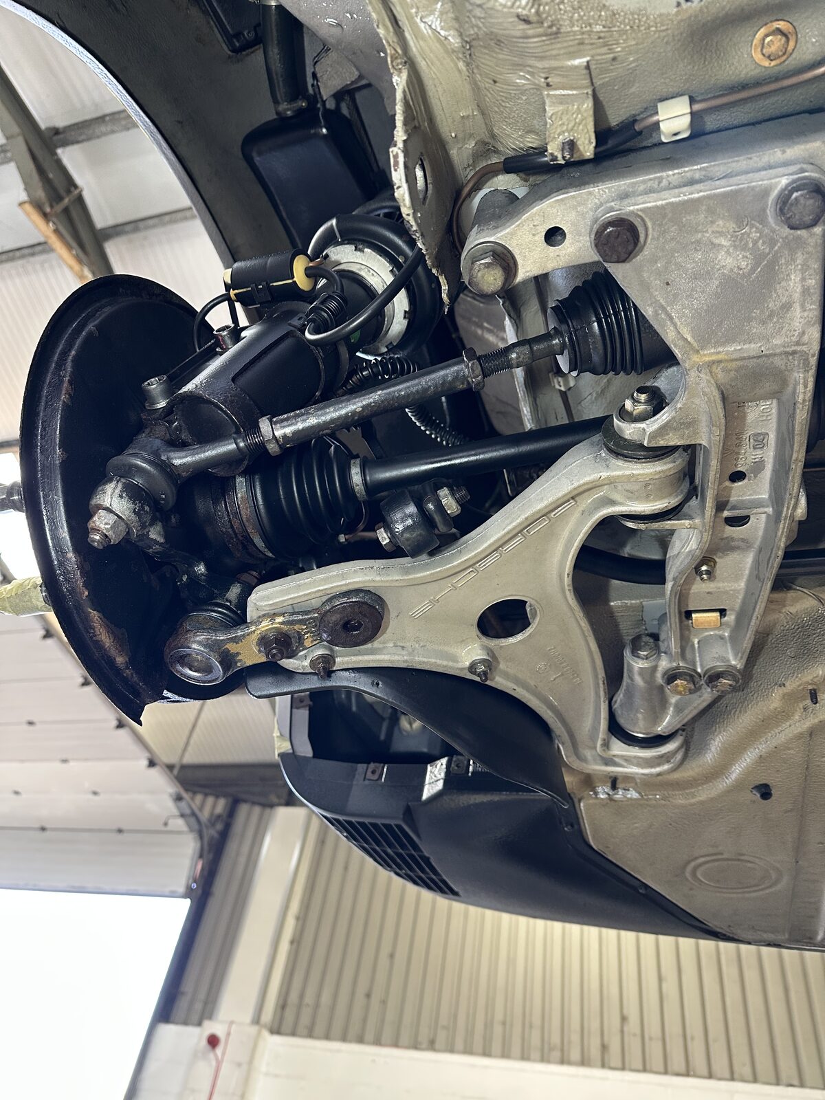 The same Porsche 911 Carrera 4 front lower arm after dry ice cleaning – the alloy arm back to a clean silver finish with the Porsche stamping visible