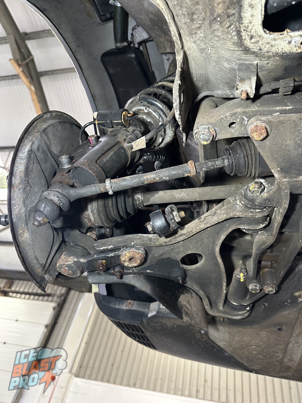Porsche 911 Carrera 4 front lower suspension arm before treatment – the alloy arm and hub caked in grime