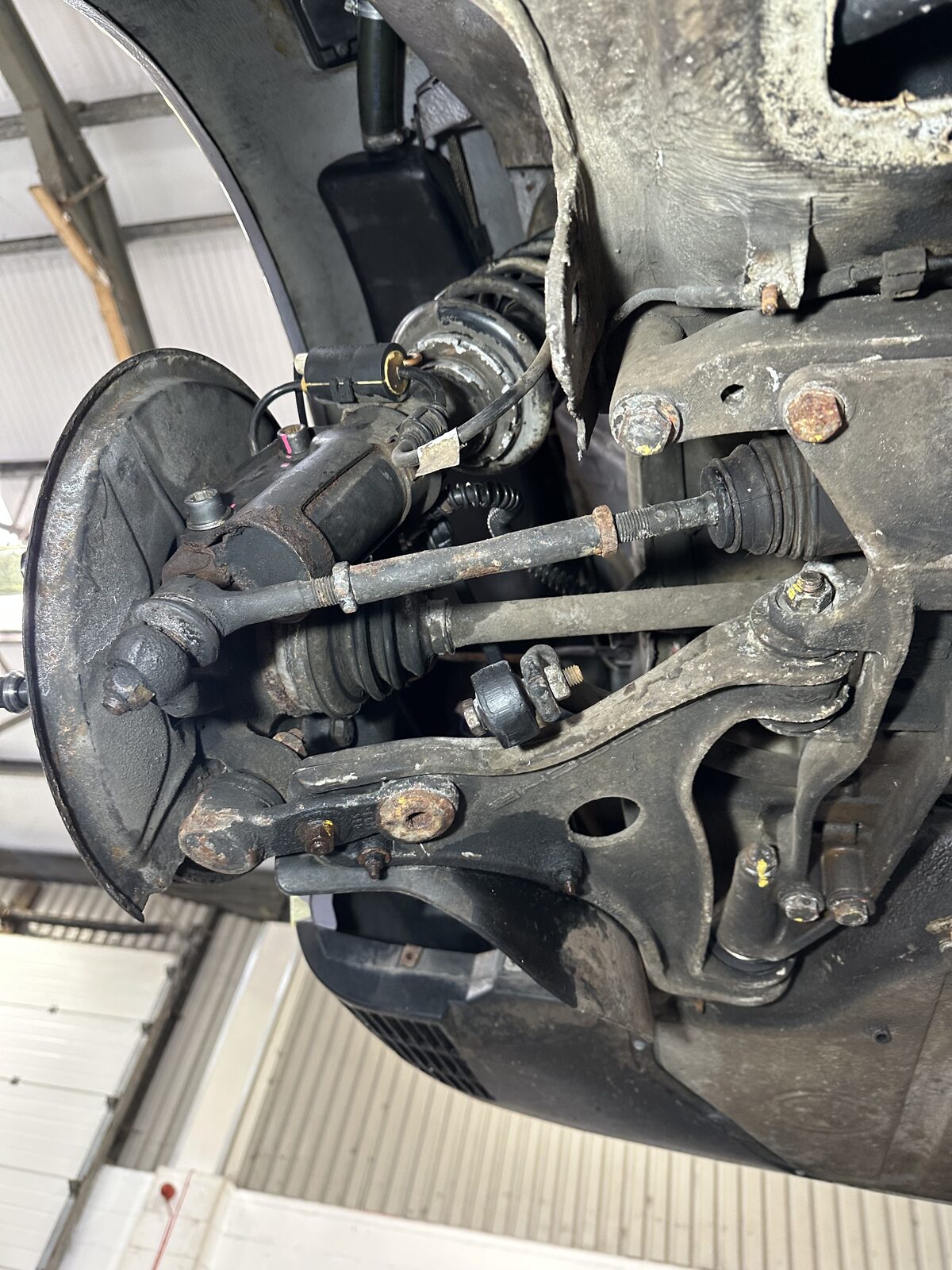 Porsche 911 Carrera 4 front lower suspension arm before treatment – the alloy arm and hub caked in grime