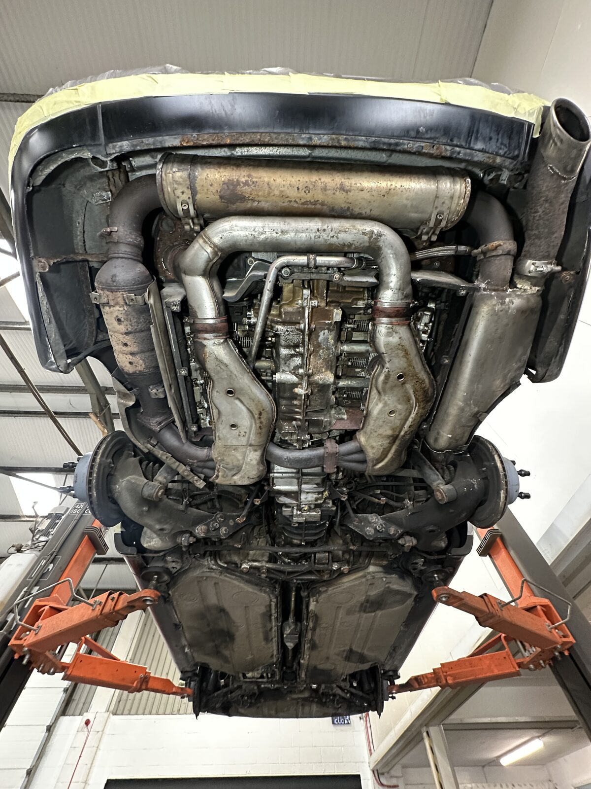 Porsche 911 Carrera 4 (964) underside before dry ice blasting – the flat-six, exhaust and heat exchangers covered in road grime and ageing wax
