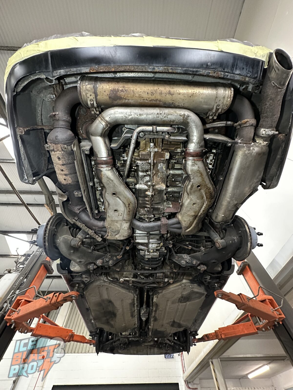 Porsche 911 Carrera 4 (964) underside before dry ice blasting – the flat-six, exhaust and heat exchangers covered in road grime and ageing wax
