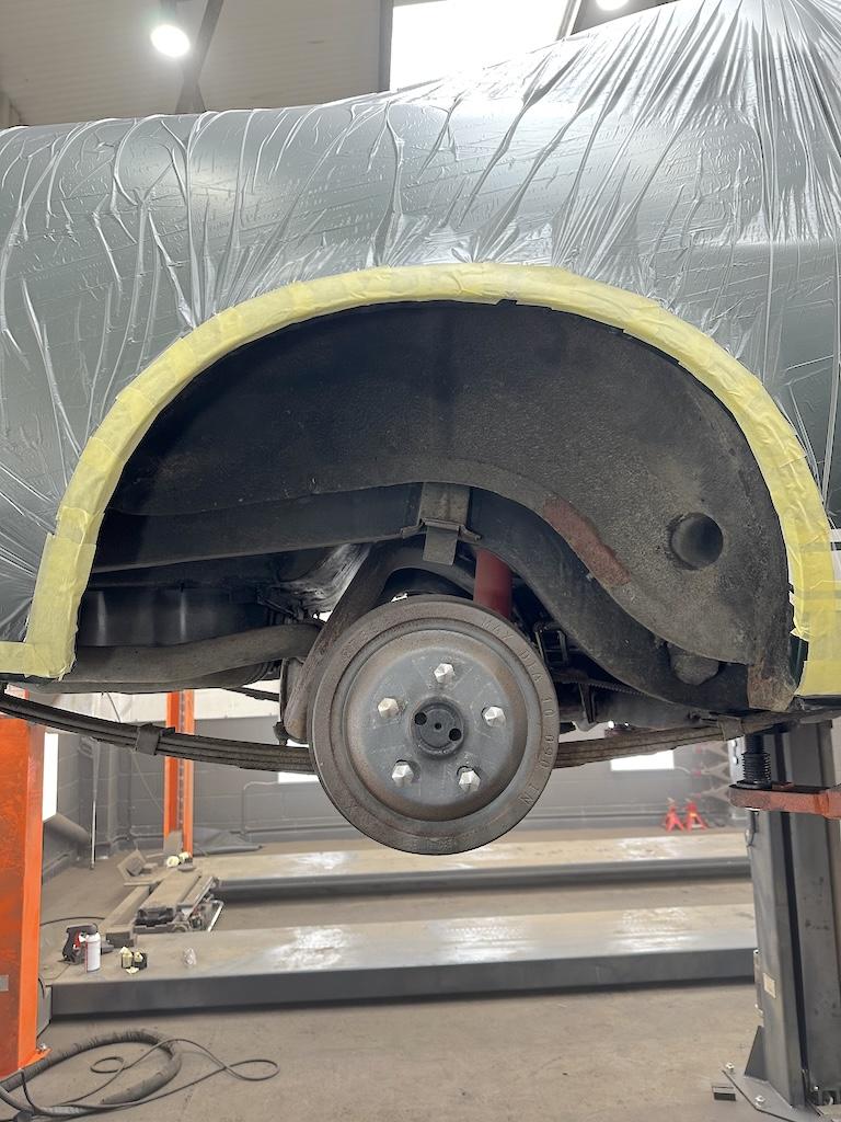Rear arch wide – Aftermarket underseal lifting at the arch lip. Brake drum showing surface oxidation.