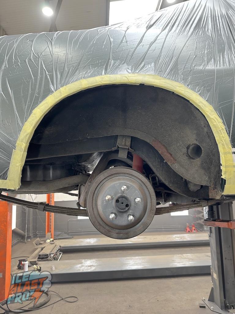 Rear arch wide – Aftermarket underseal lifting at the arch lip. Brake drum showing surface oxidation.