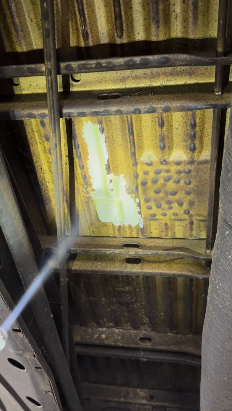 Dry ice blasting a corrugated metal floor section during a camper restoration, revealing original paint.